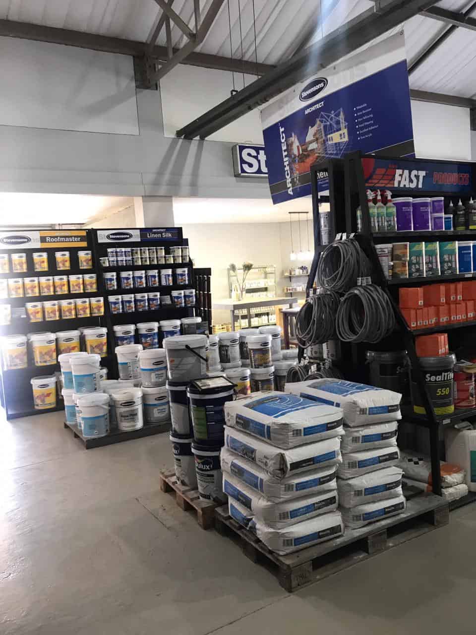 Hardware and paint store section with stacked bags of building materials and paint containers.