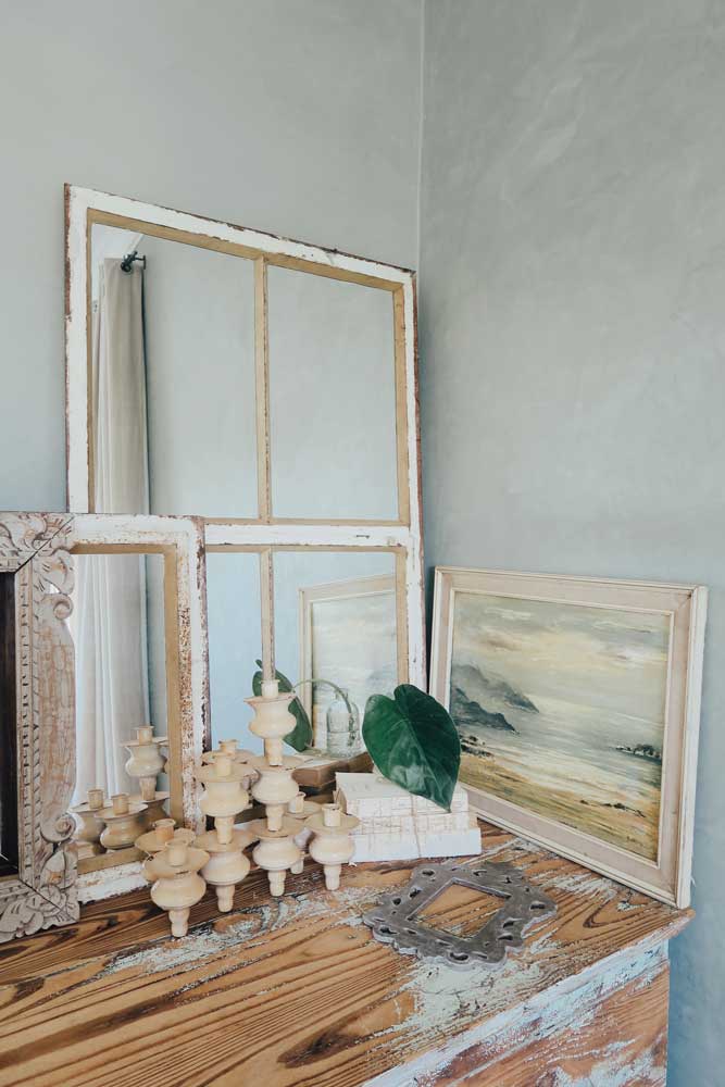 Rustic wooden dresser with vintage mirrors, candlesticks, and coastal painting